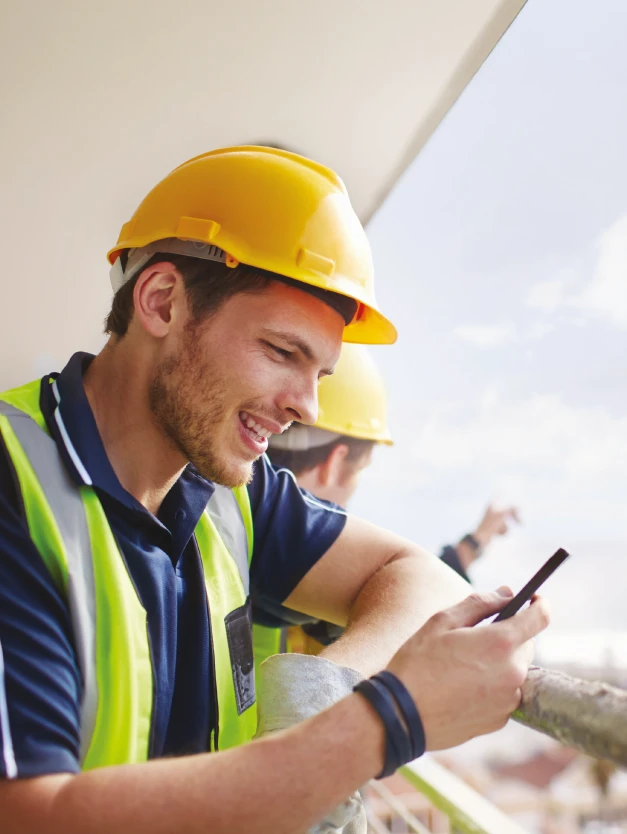 Image d'un homme sur un chantier qui regarde son téléphone portable