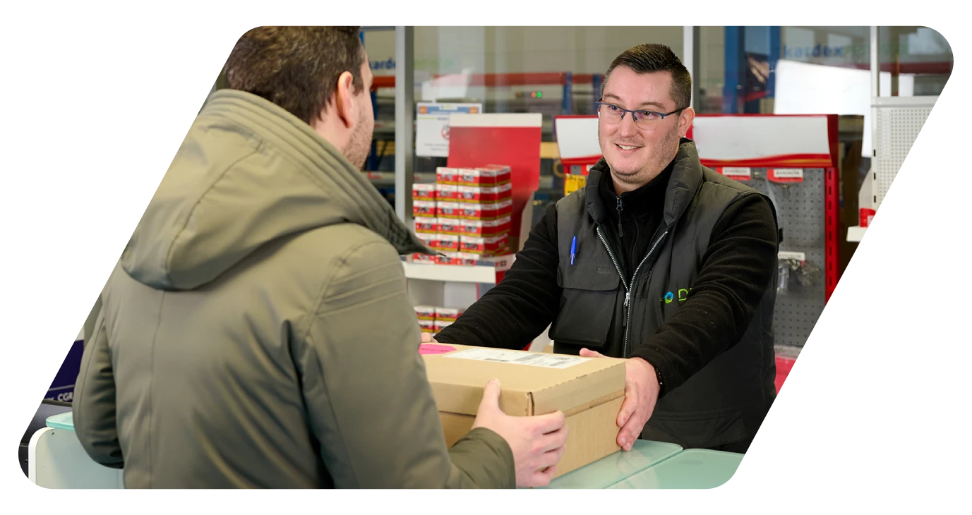 Un vendeur remet un colis à un client au comptoir d'une agence CGR-DBS.